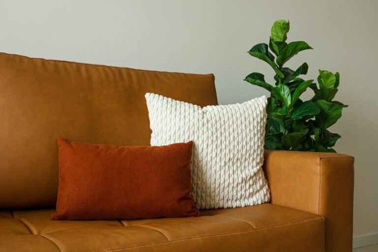 18x18 pillow inserts styling idea: a cream knit pillow on a tan leather sofa beside a green plant