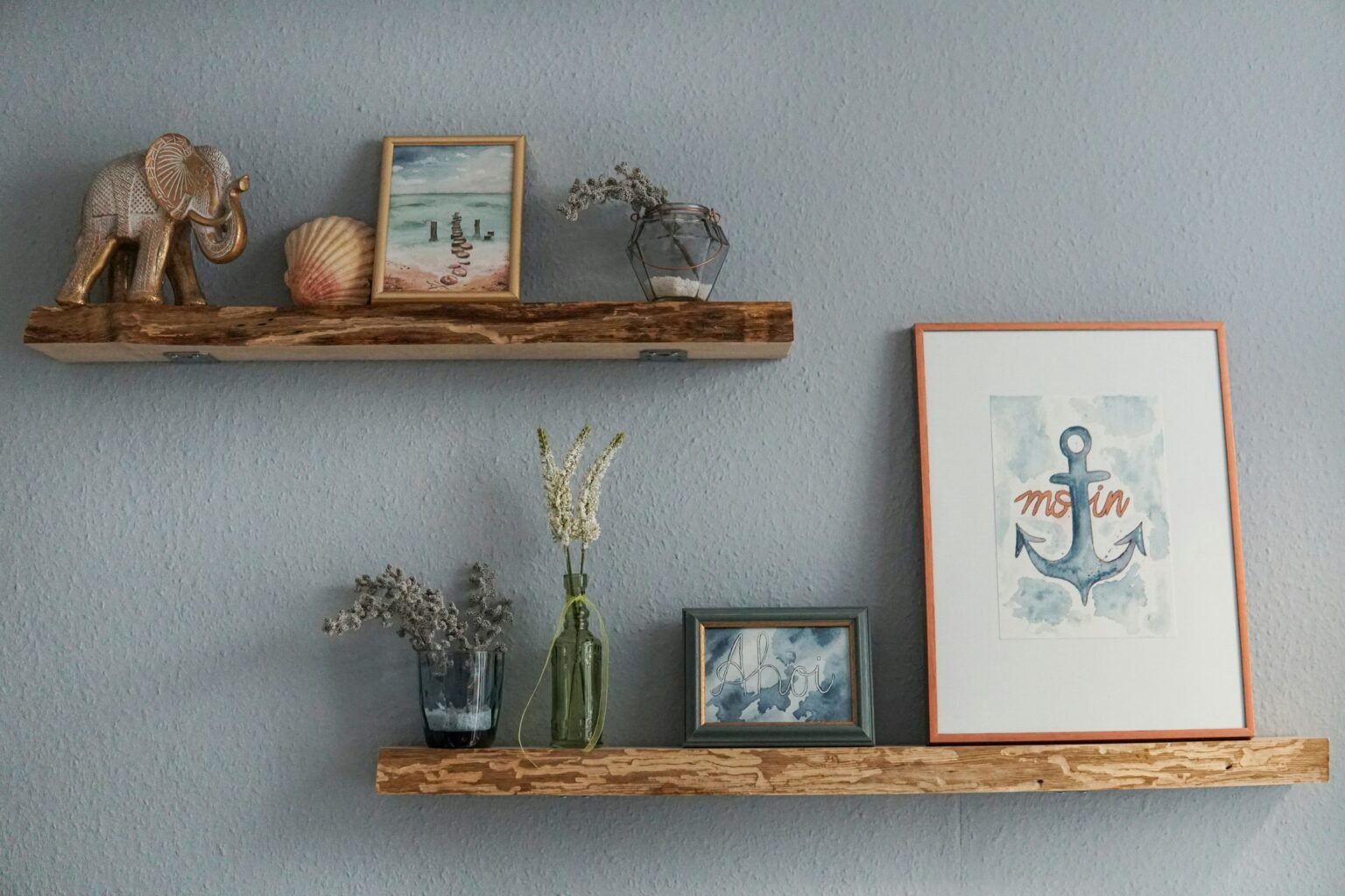 Acrylic wall shelves styling idea: two floating shelves with framed art, a vase and small decor on a gray wall
