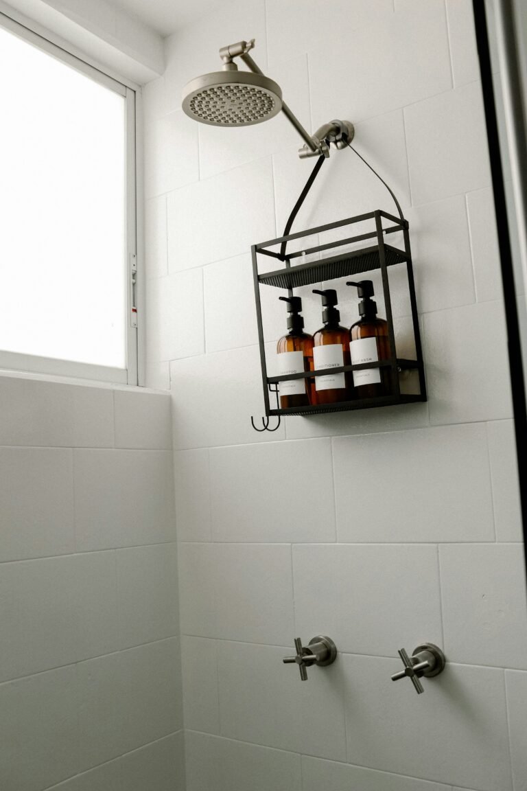 Shower wall where an adhesive shower caddy keeps soap and bottles organized