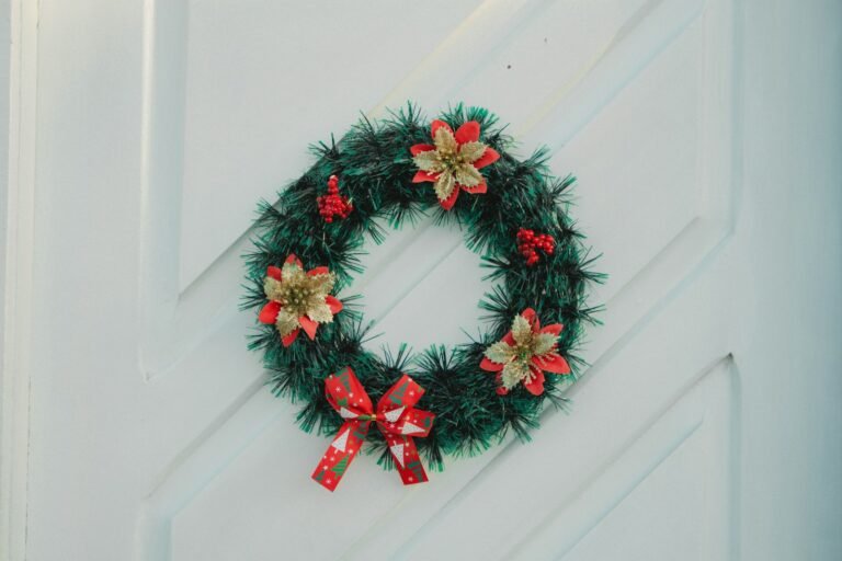 Adjustable wreath hanger idea: a red and green Christmas wreath centered on a white front door