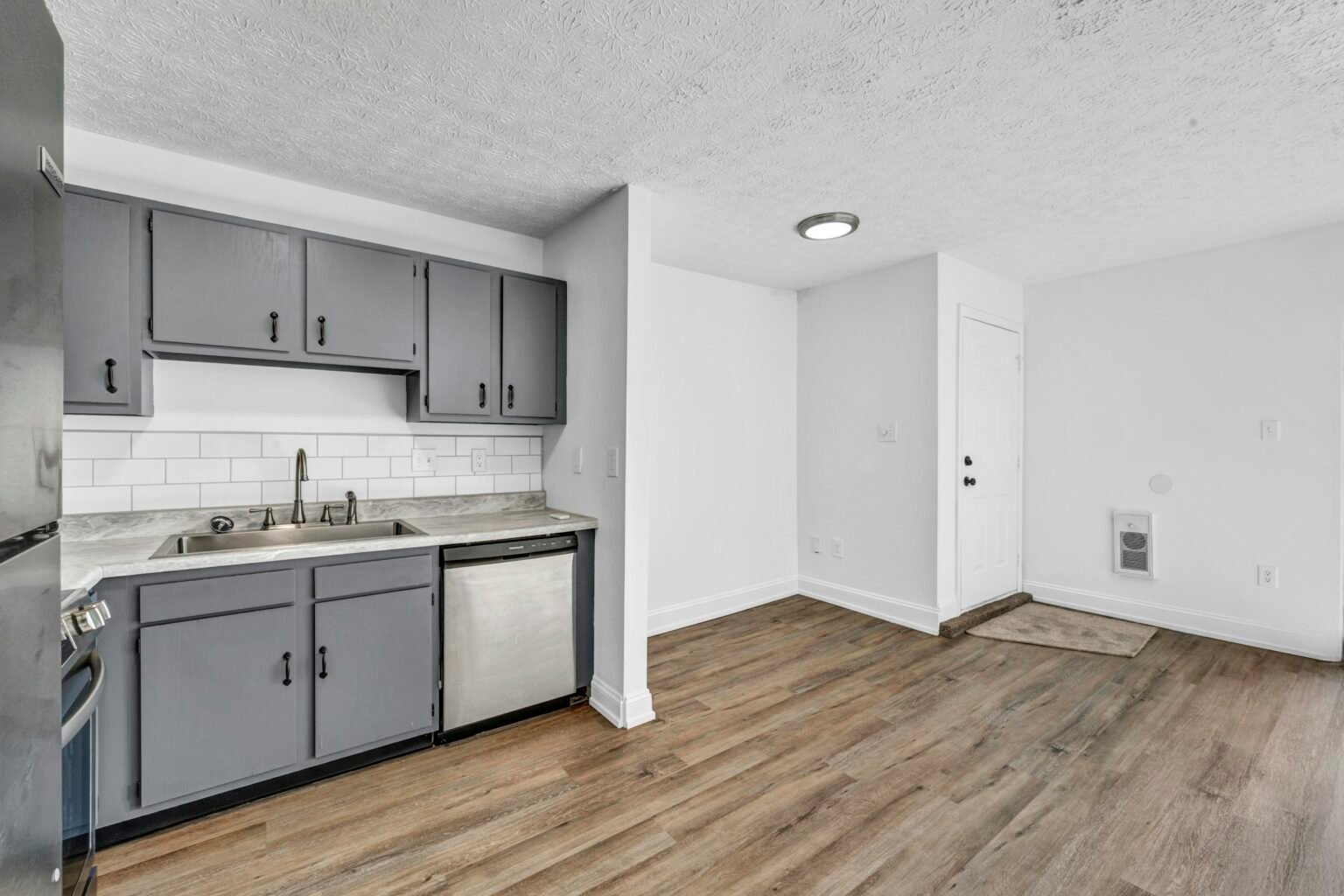 Anti-fatigue kitchen mat in front of kitchen cabinets on a wood-look floor