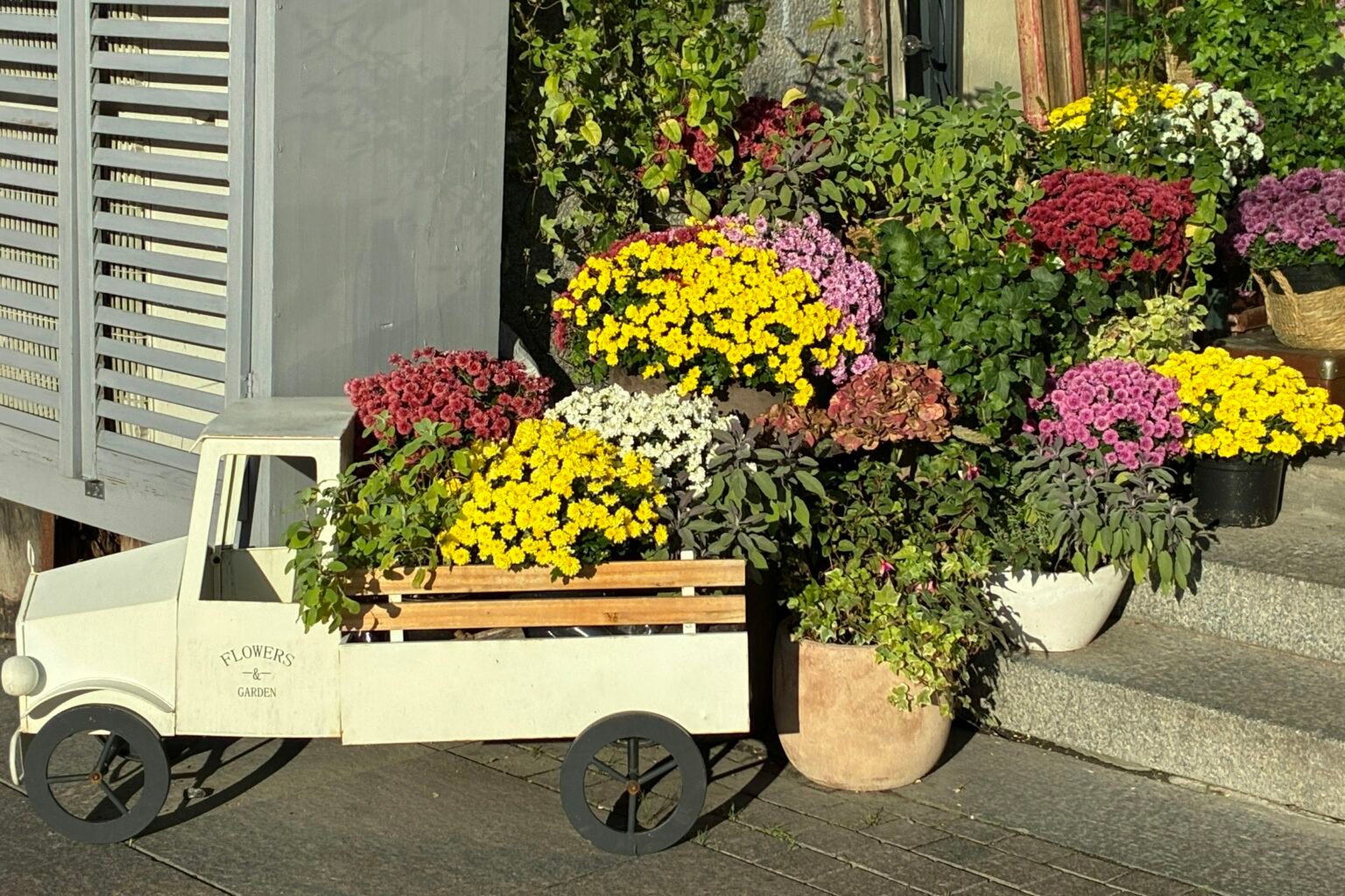 Artificial fall flowers for outdoor planters: yellow and purple mums in pots by a front door