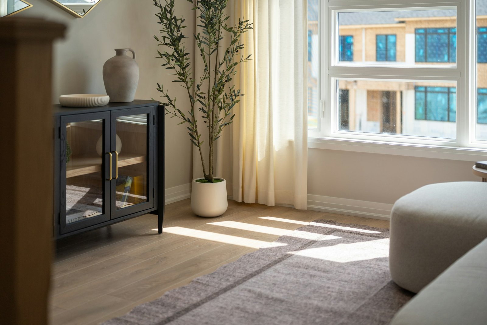 Artificial olive tree style: a potted olive tree beside a black cabinet in a living room