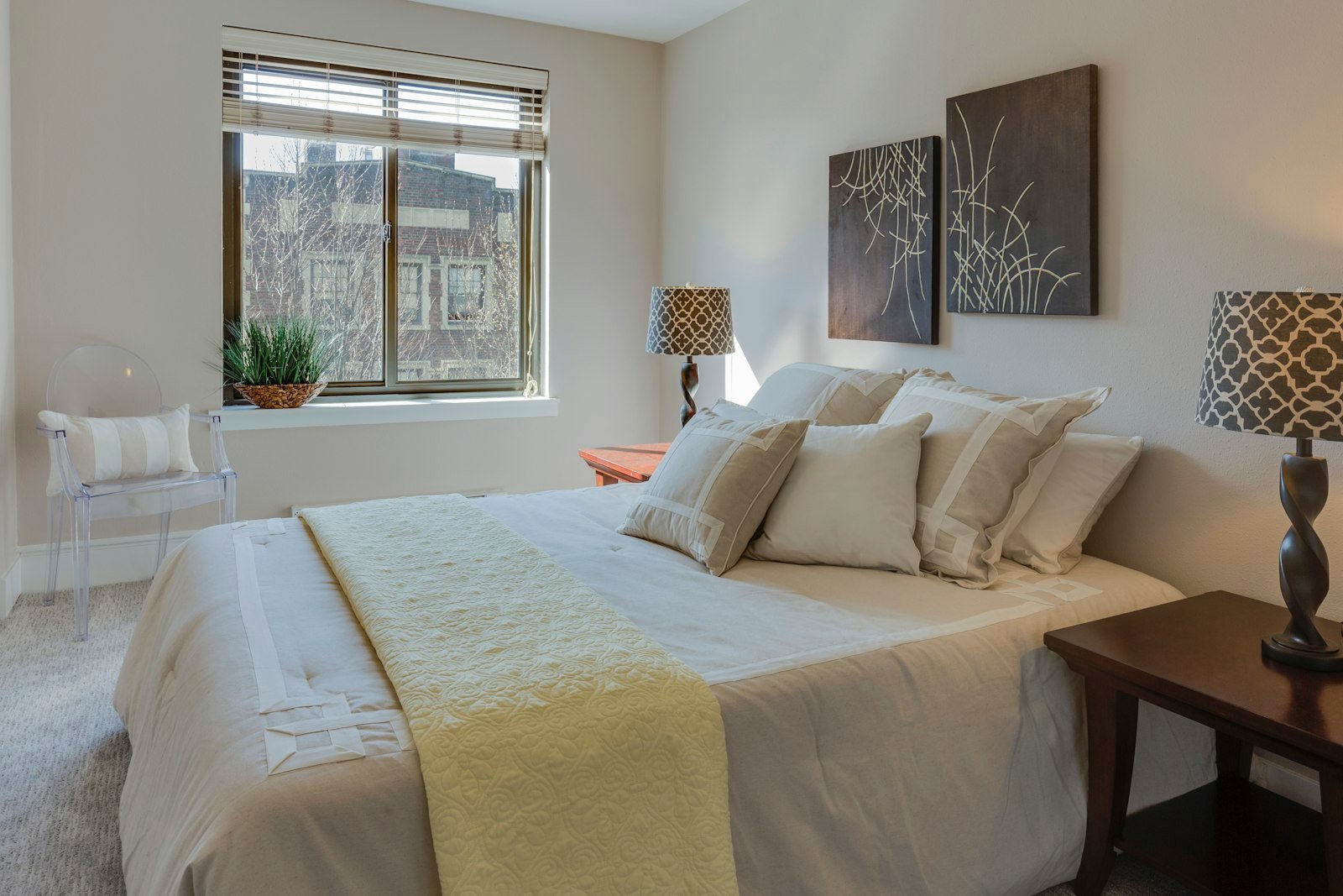 Beige comforter set on a king bed with layered neutral pillows in a bright bedroom