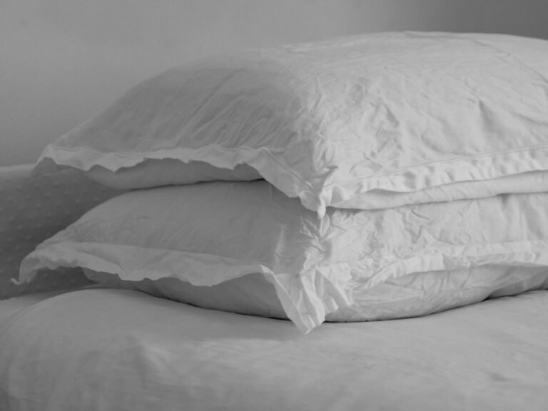 Best bed pillows stacked on a made bed with white bedding