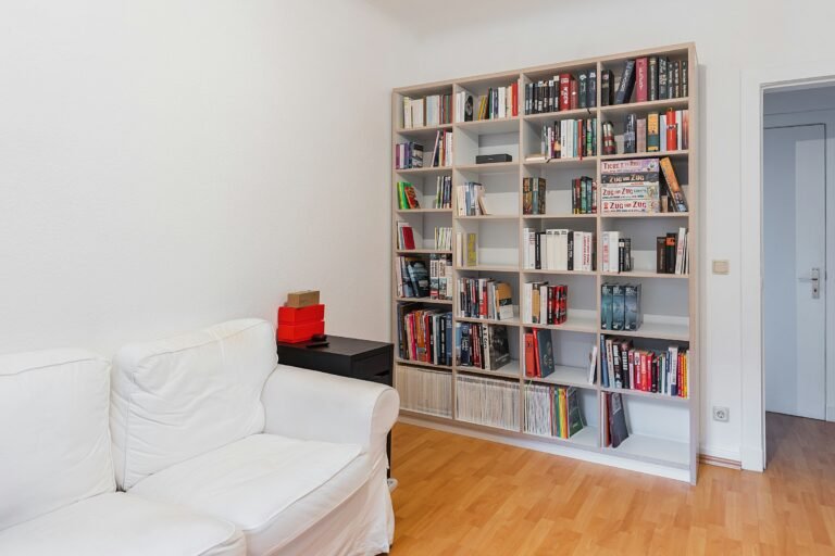 Best bookshelves for a small living room: a tall open bookcase full of books beside a white sofa