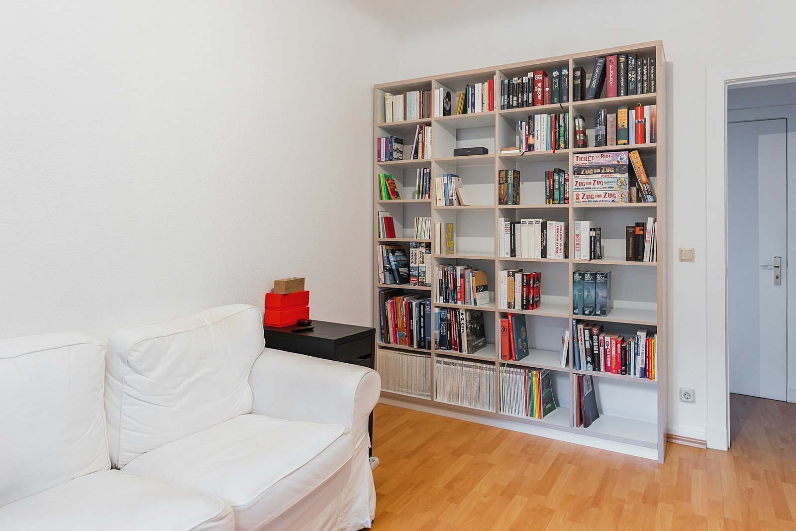 Best bookshelves for a small living room: a tall open bookcase full of books beside a white sofa