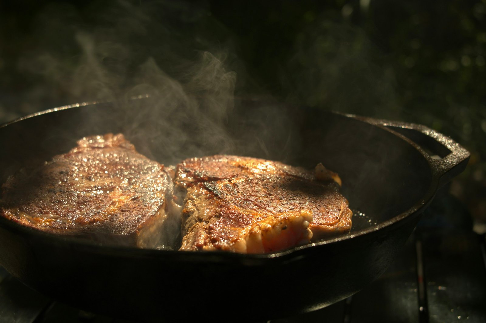 Best cast iron skillet for searing: two steaks sizzling in a black cast iron pan