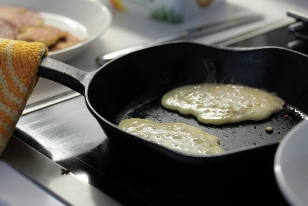 Pancakes cooking in a cast iron pan on a smooth electric range, the job the best cast iron skillet for glass top stove should handle
