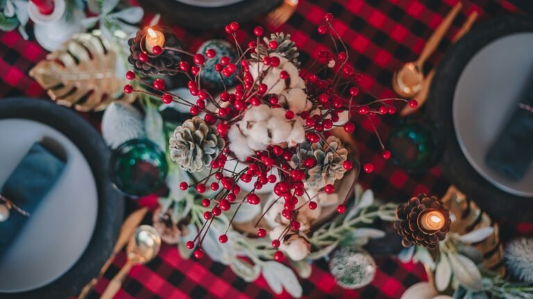 Christmas table runner idea: red and black buffalo plaid table linen with pine cones, red berries and gold flatware on a holiday dinner table