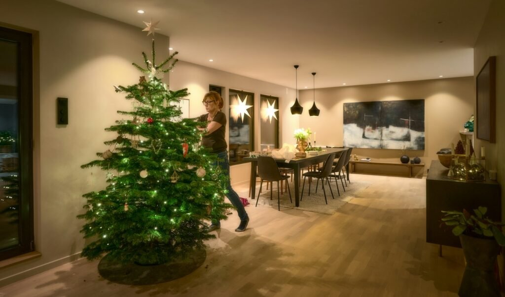 Best Christmas tree lights: warm white mini lights glowing on a tall tree in a modern living room