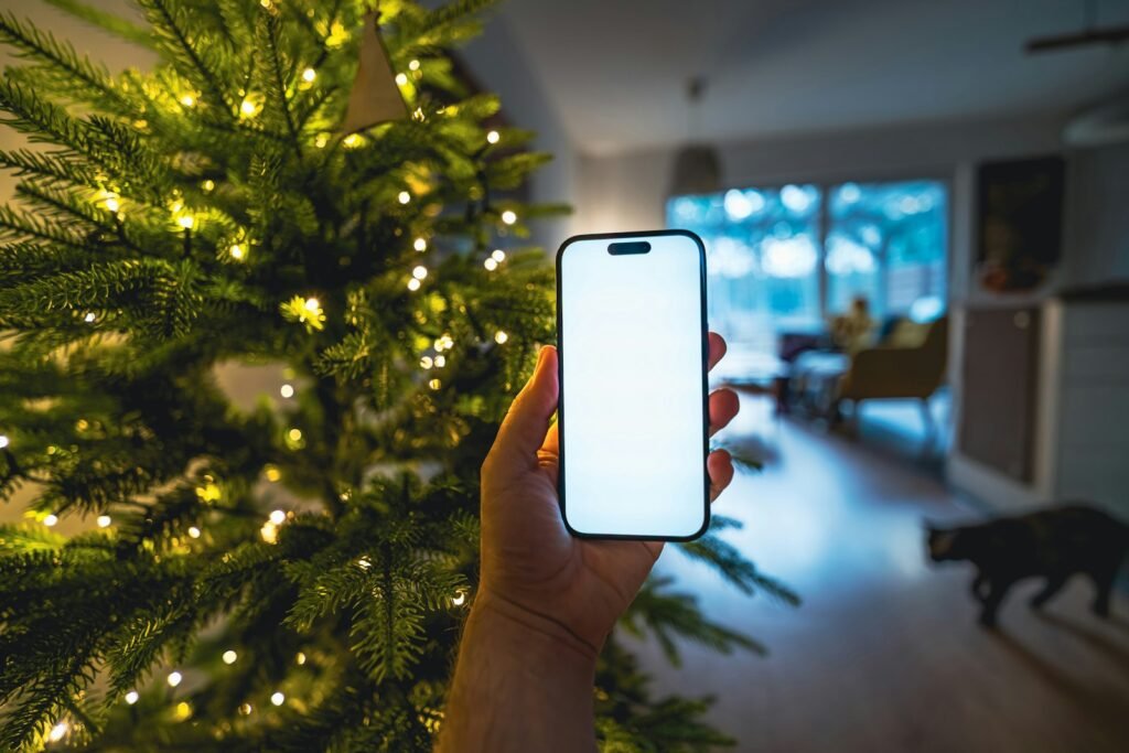 Smart Christmas tree lights controlled from a phone app next to a lit tree in a living room