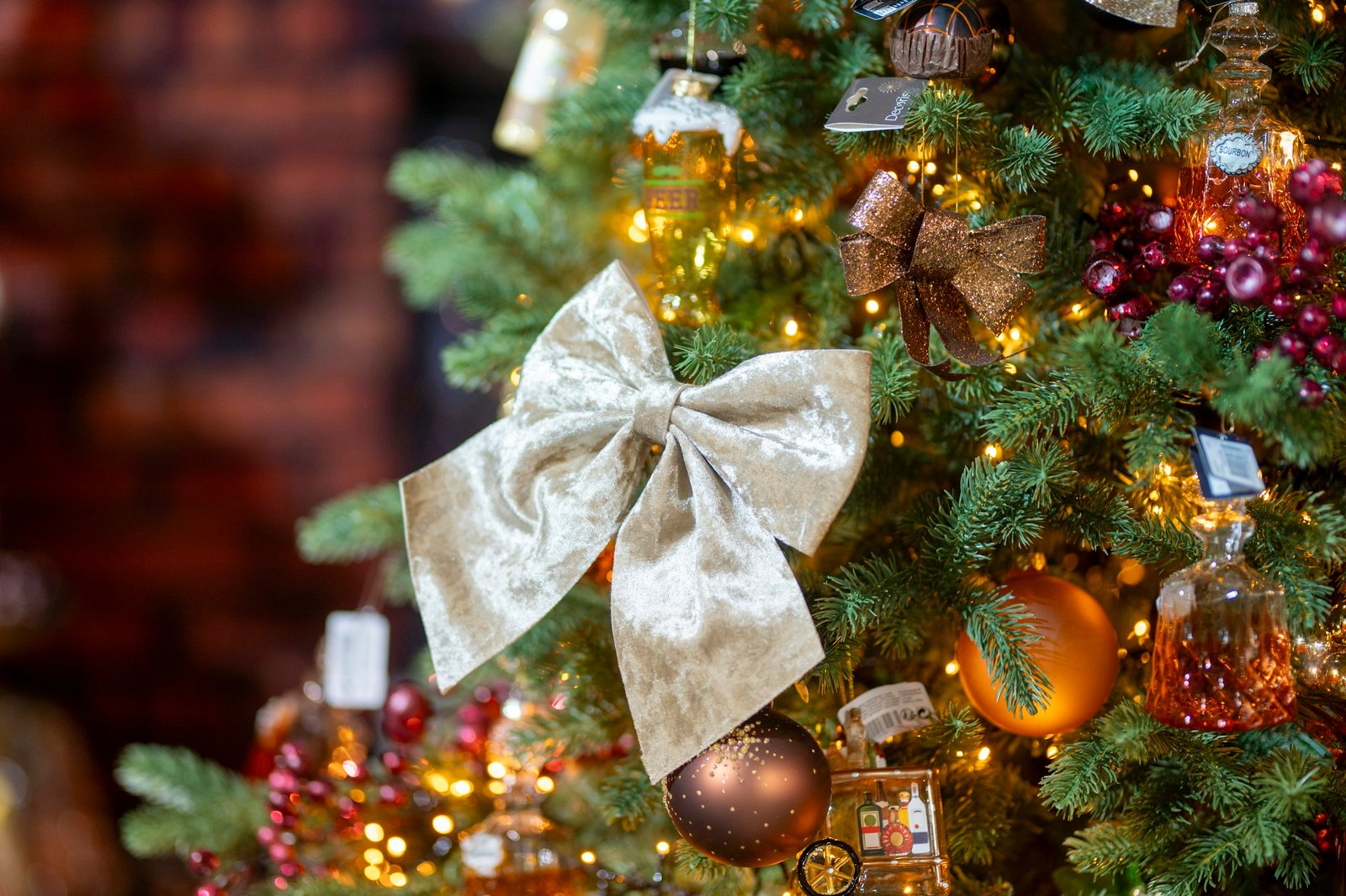 Best christmas tree ribbon idea: a champagne velvet bow on a lit Christmas tree with gold and burgundy ornaments
