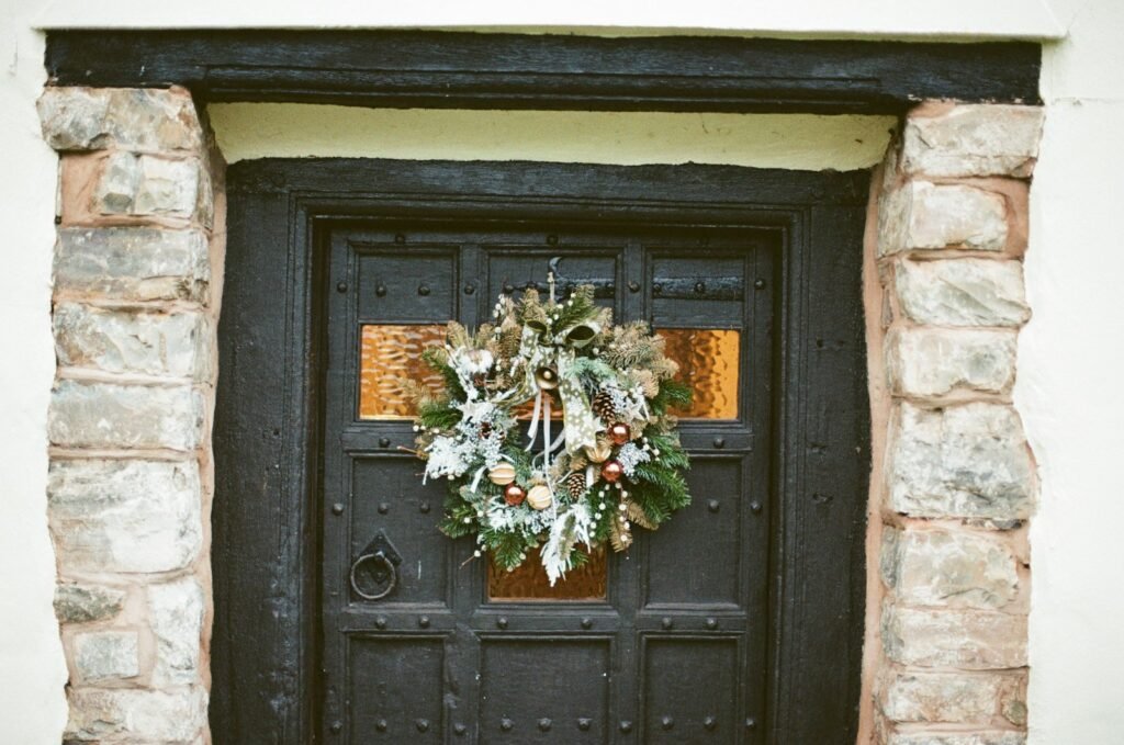 Christmas wreaths for front door: a frosted pine wreath centered on a dark wooden door