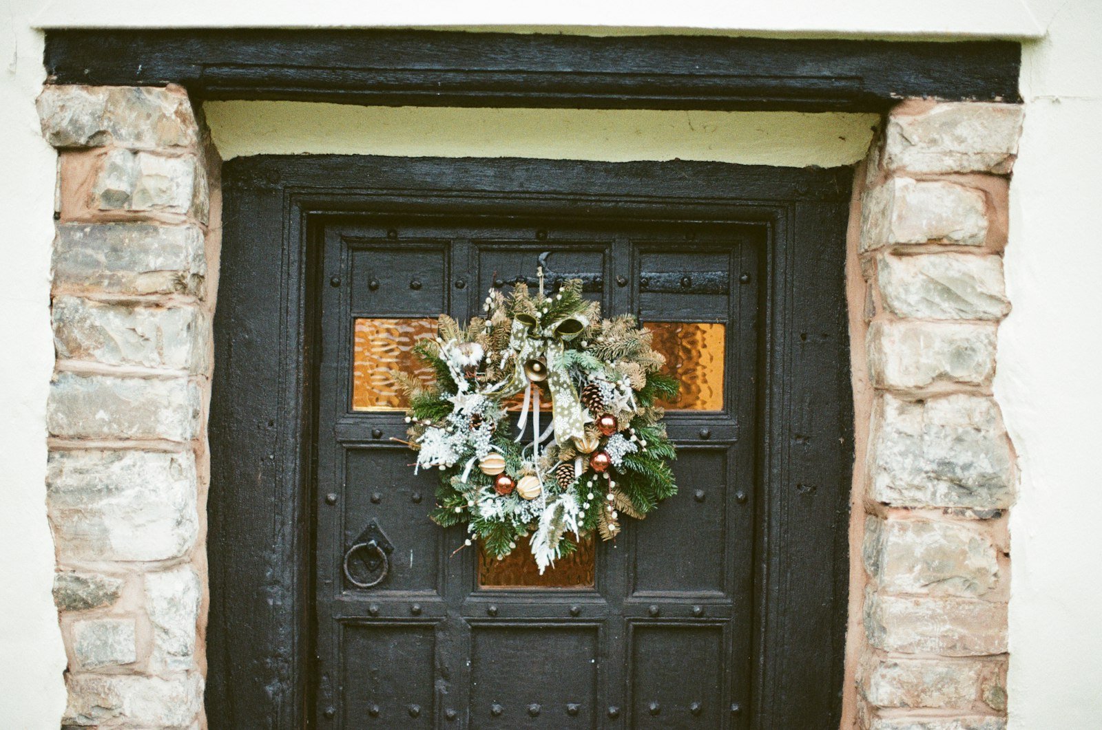 Christmas wreaths for front door: a frosted pine wreath centered on a dark wooden door