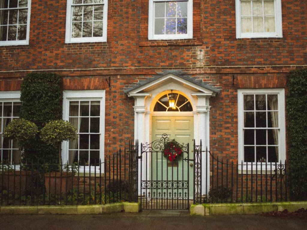 Red brick house with a pale green door and a wreath sized for the door, showing what size wreath for front door looks balanced