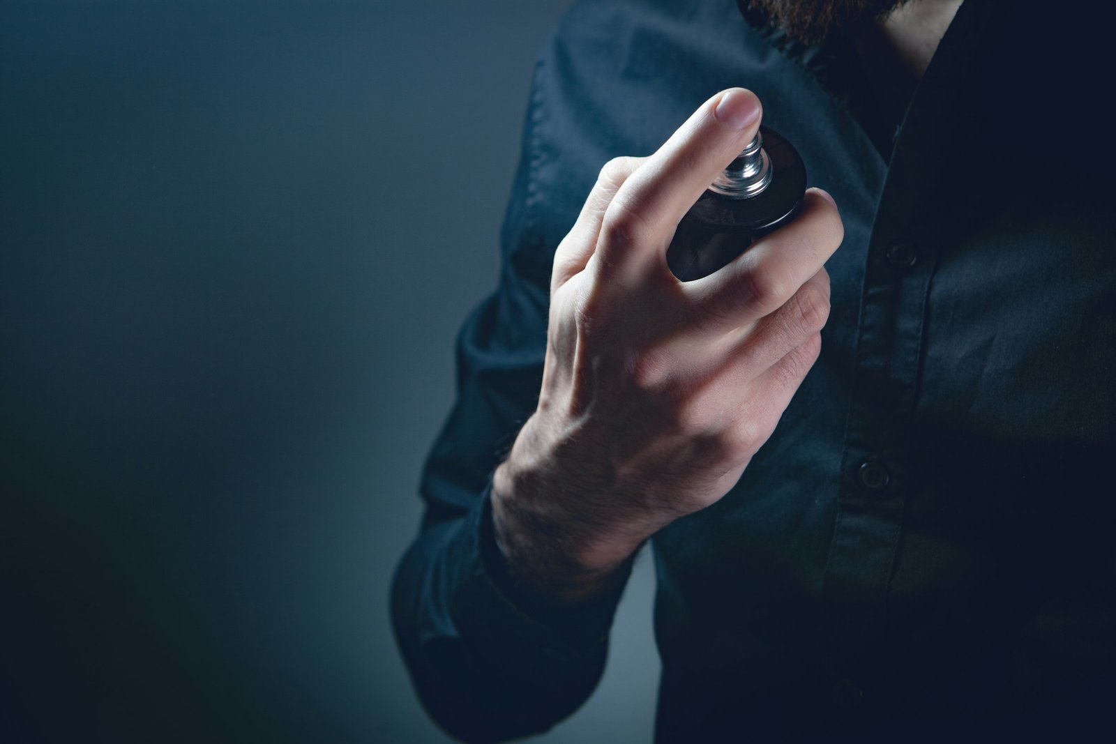 Cologne gift sets for men: a man in a dark shirt spraying cologne on his neck