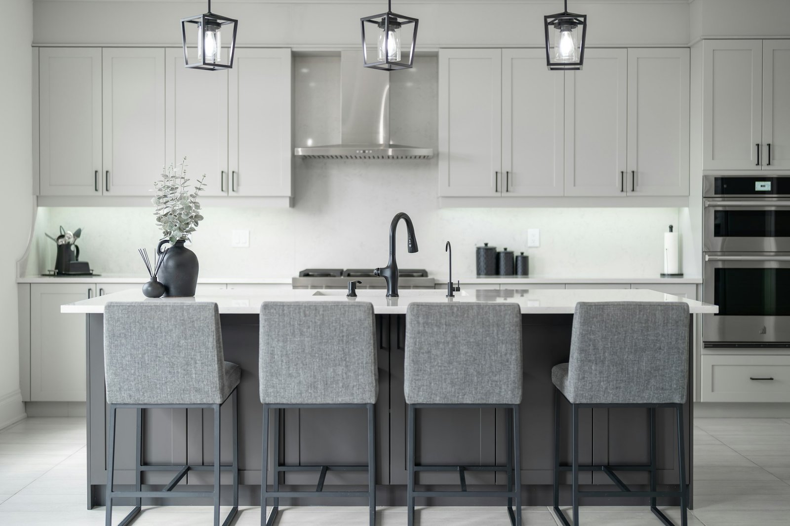 Best counter stools: four gray upholstered counter height stools with metal legs at a white kitchen island