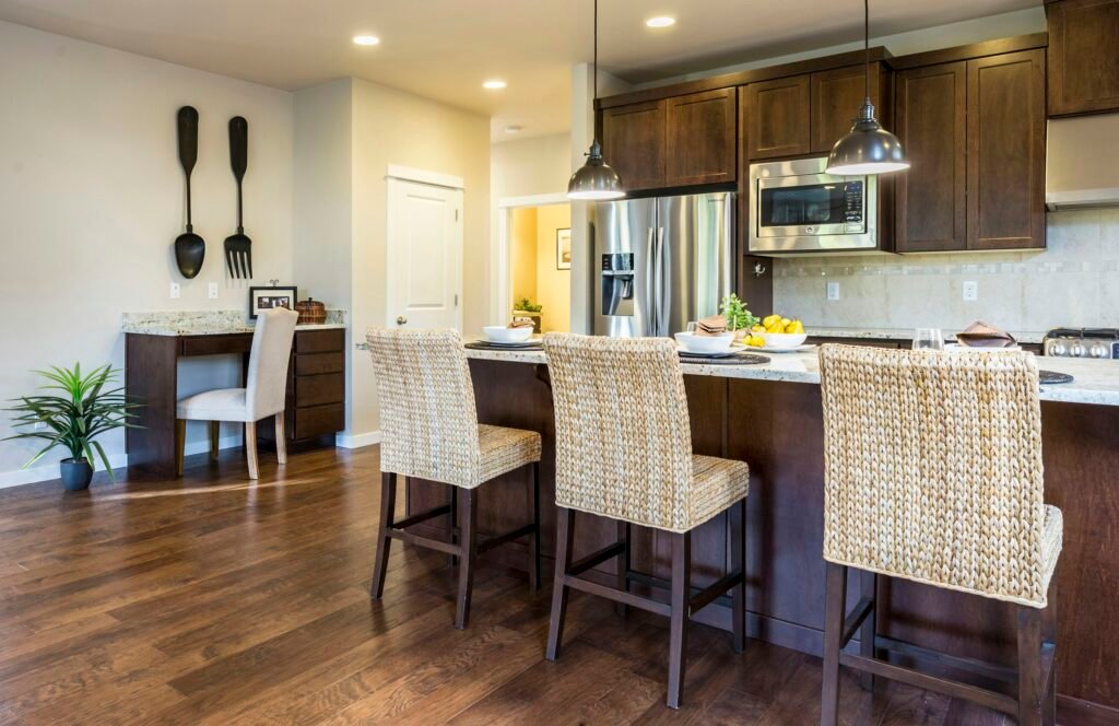Woven counter height bar stools with backs at a dark wood kitchen island with pendant lights