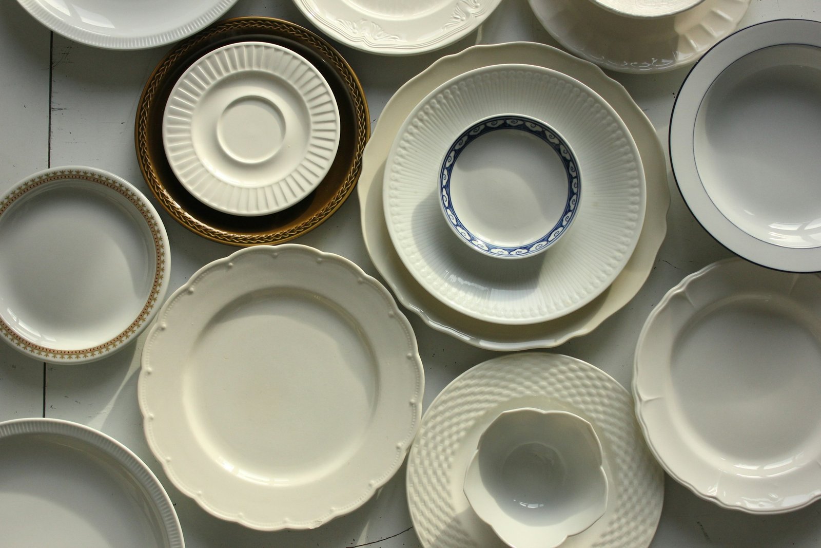 Best dinnerware sets: white stoneware and porcelain dinner plates, salad plates and bowls laid out on a table