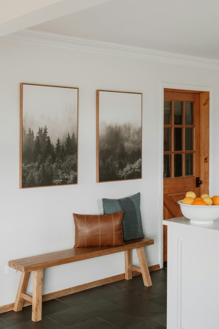 Wooden entryway bench with pillows below framed art by the front door, the spot an entryway bench with shoe storage fills