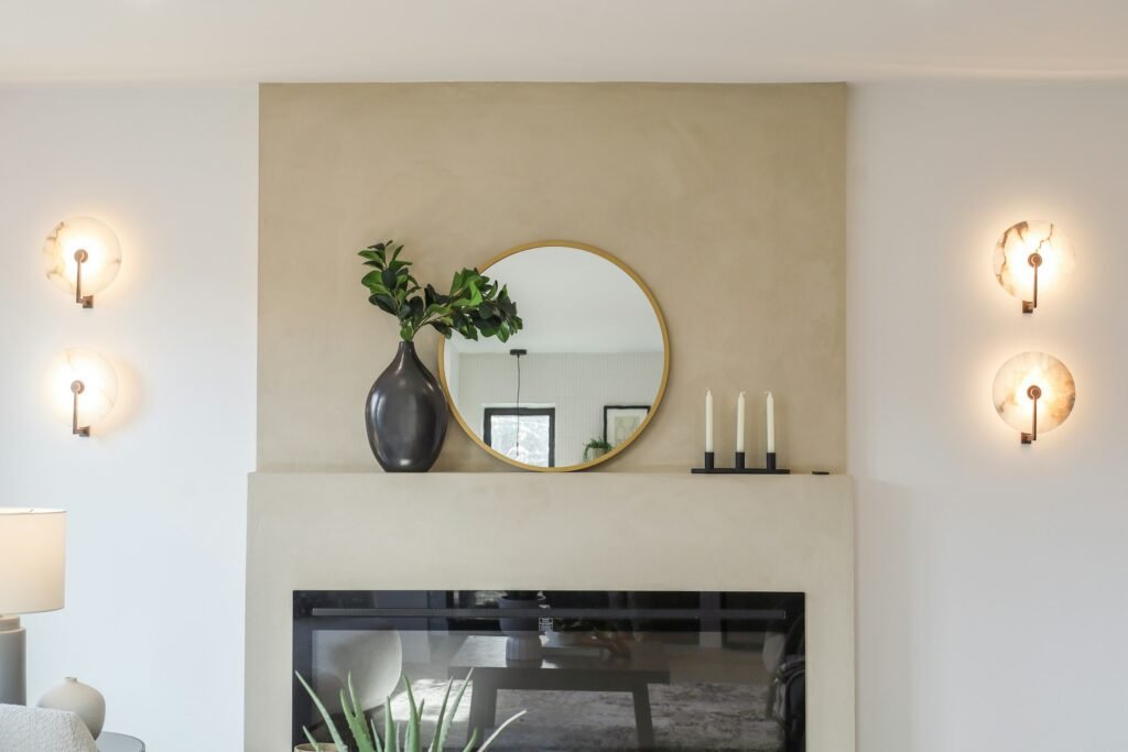 Best floor mirrors and wall mirrors: a round gold-framed wall mirror above a fireplace mantel in a bright living room