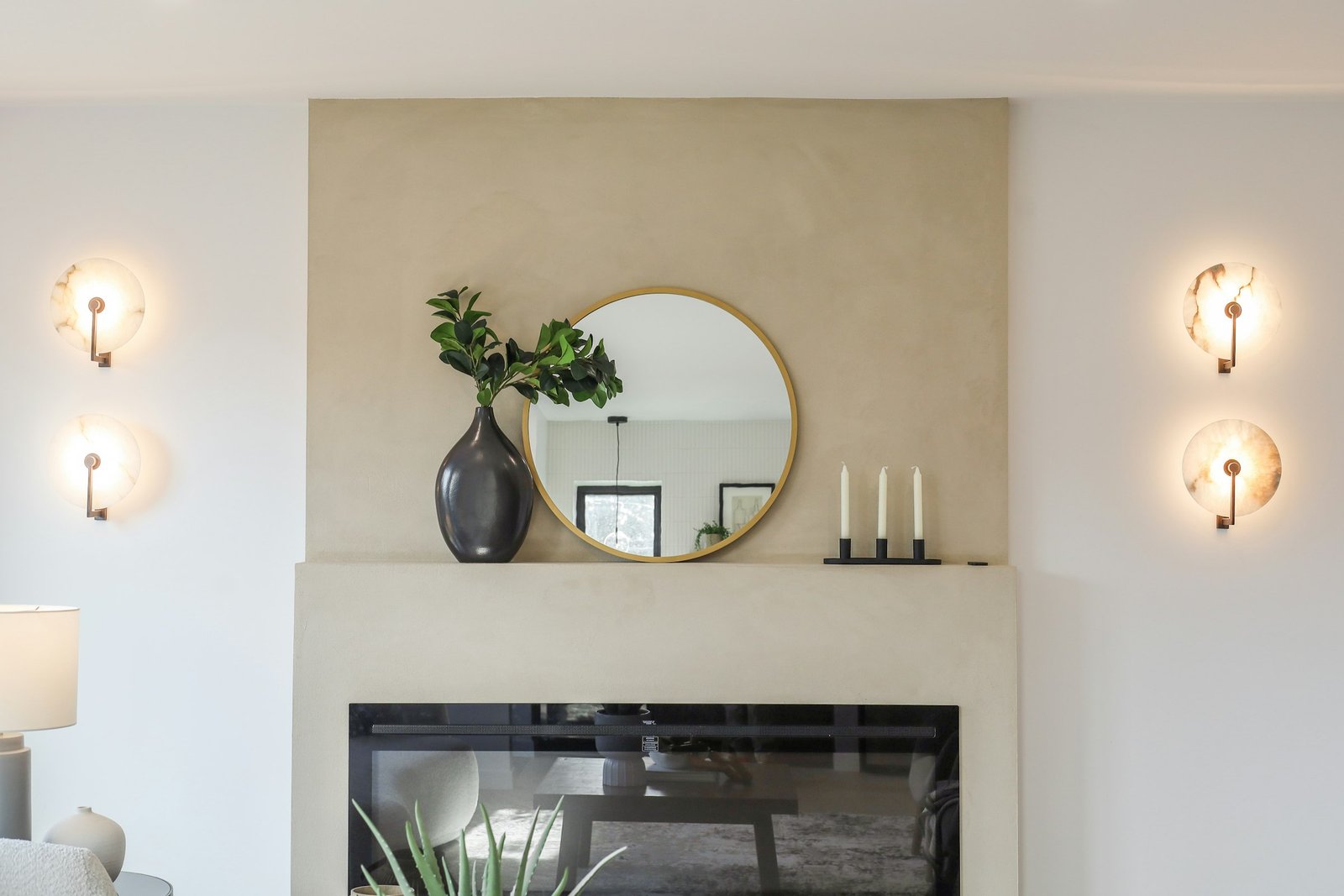 Best floor mirrors and wall mirrors: a round gold-framed wall mirror above a fireplace mantel in a bright living room