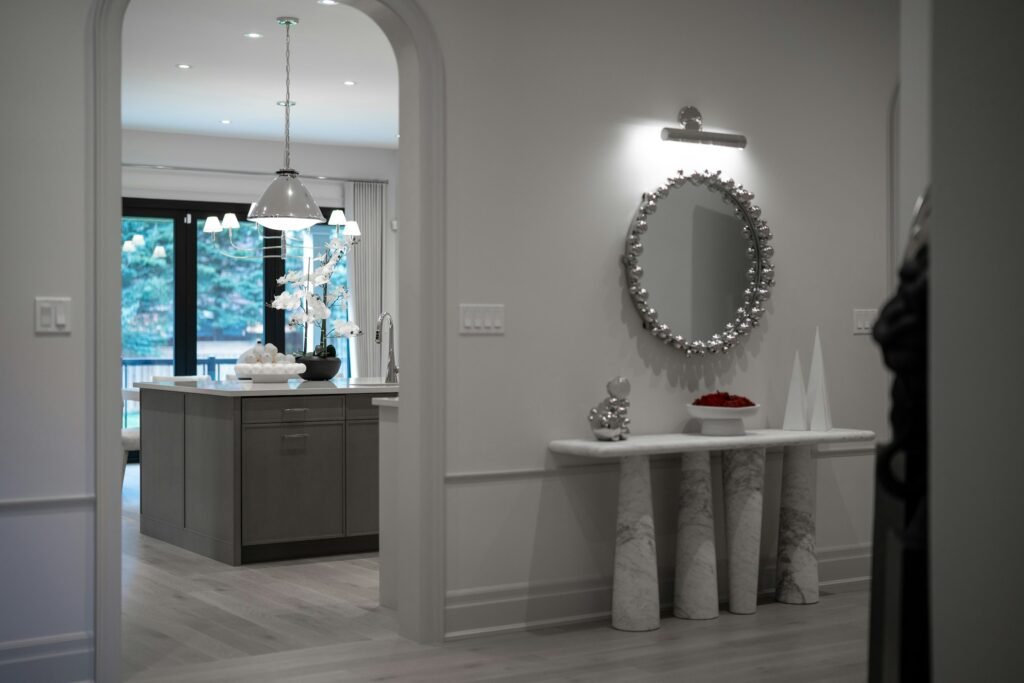 Round decorative wall mirror above a console table in an entryway, an example of a mirror to make room look bigger