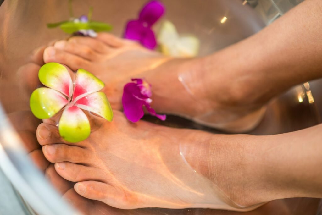 Foot spa massager idea: feet soaking in warm water with flowers in a bowl