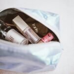 Best hanging toiletry bag for women: an open metallic makeup bag filled with cosmetics