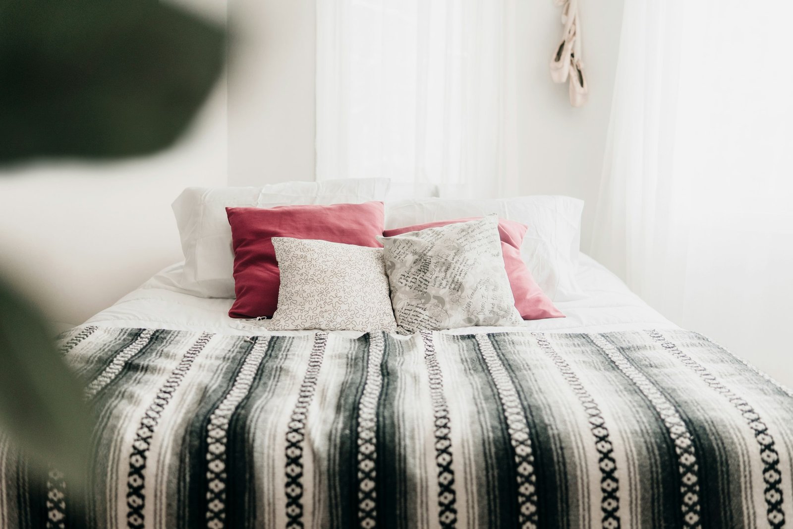 Best heated blanket: a black and white striped blanket on a white bed with pink and gray pillows
