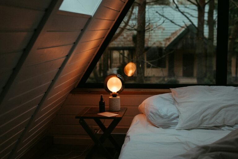 Best heated mattress pad guide: a made bed beside a cold cabin window with a warm bedside lamp