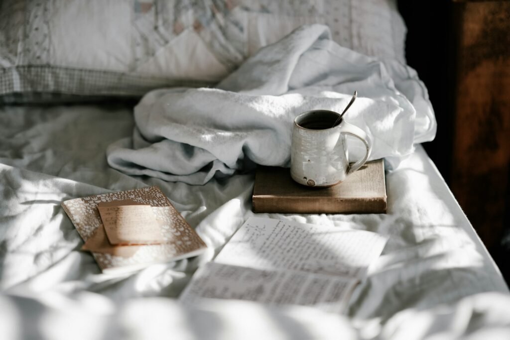 Heated mattress pad vs heated blanket: a cozy bed with a soft blanket, a mug and an open book