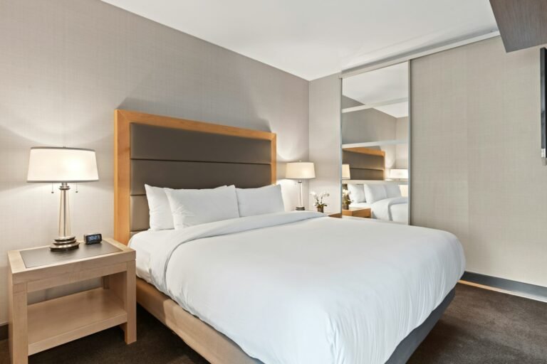 Best king mattress in a box made up with white bedding on an upholstered king bed