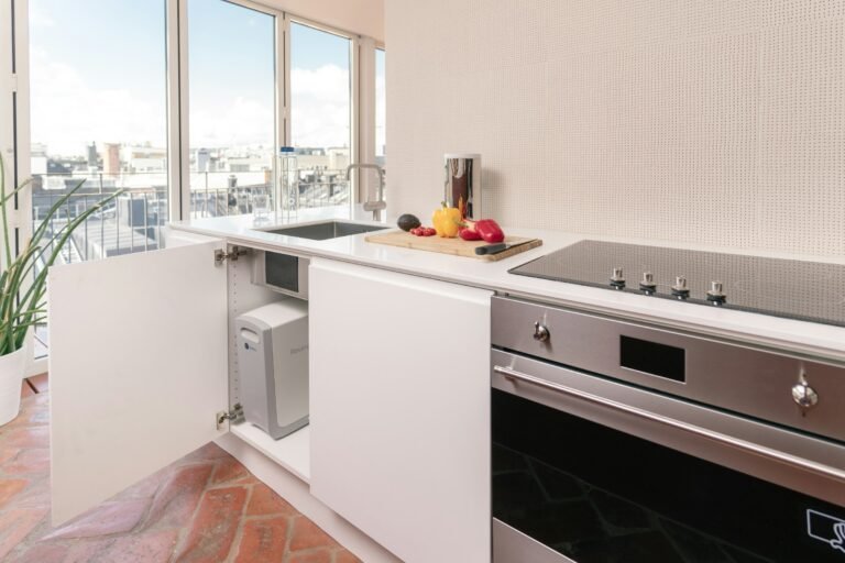 Best kitchen trash can setup: a bright white kitchen with an under-sink cabinet bin
