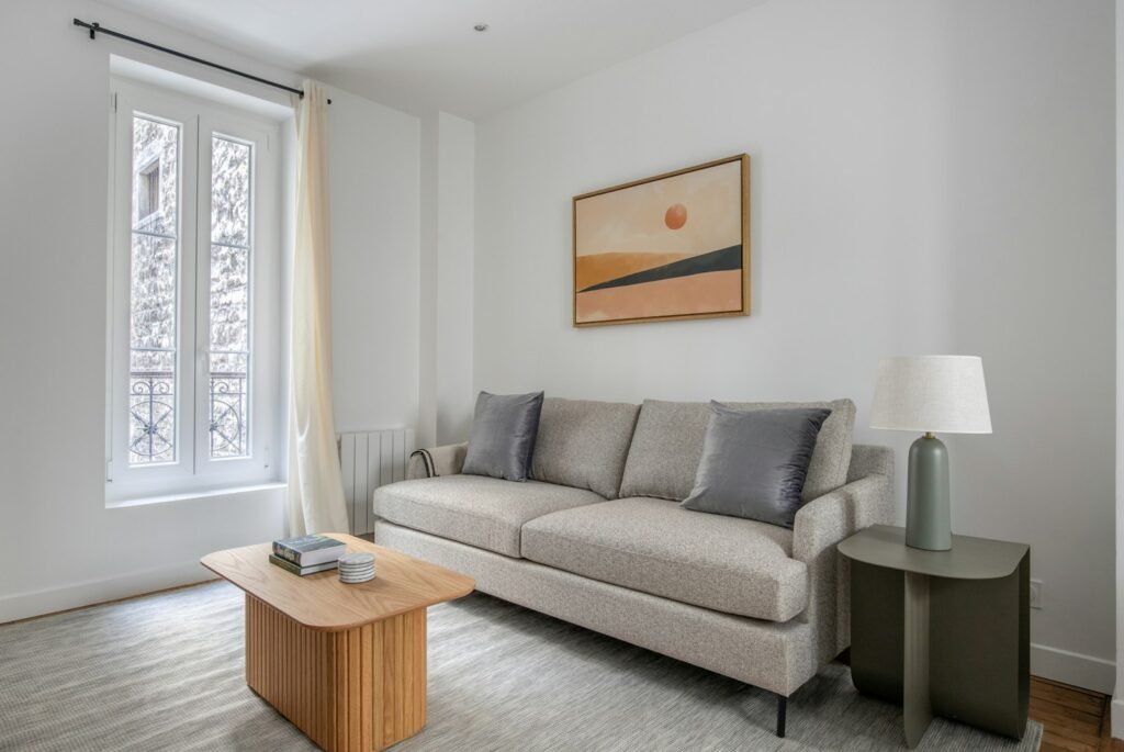 Small living room with a compact wooden coffee table in front of a light gray sofa, showing coffee table size to couch proportions
