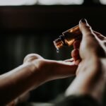Best luxury beard oil: a hand tipping drops from an amber glass dropper bottle