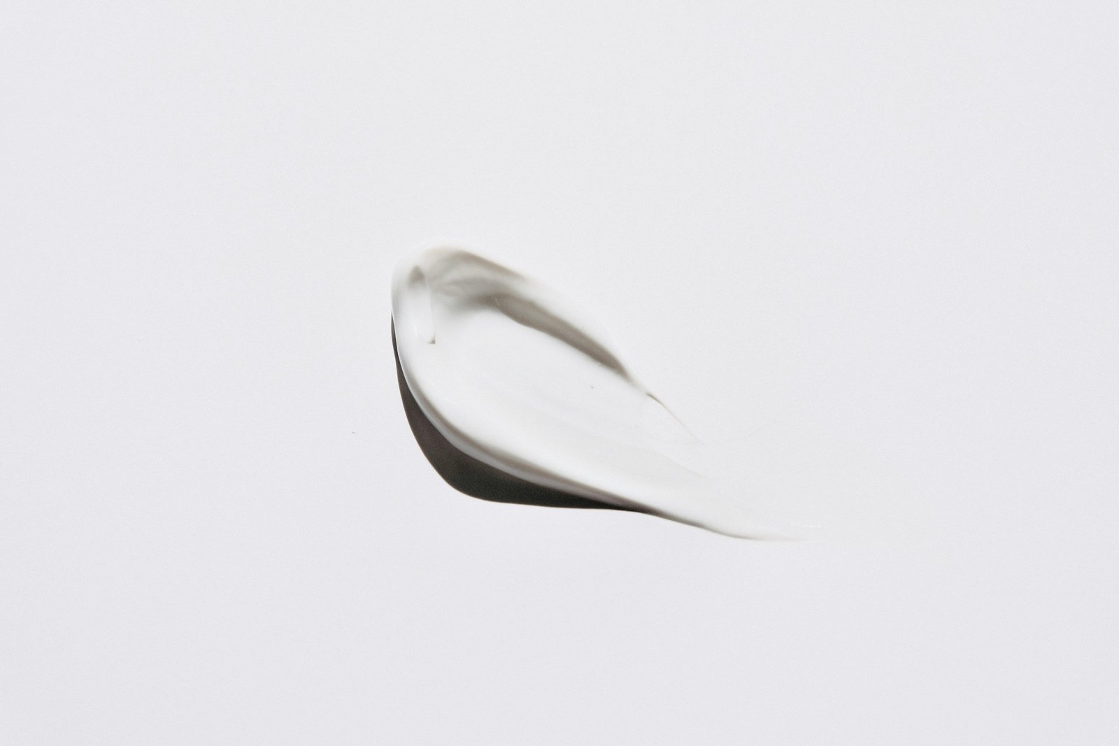 How to apply eye cream: a small smear of white eye cream texture on a plain white background