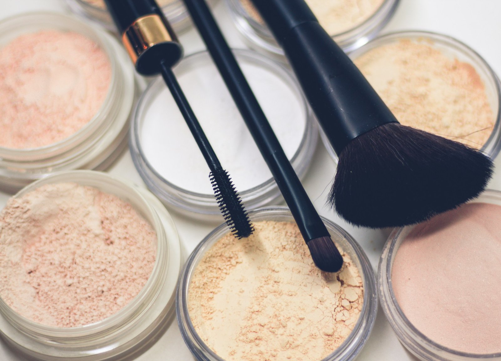 Best luxury foundation shade range: open pots of ivory, beige and warm powder shades with a black kabuki brush and makeup brushes