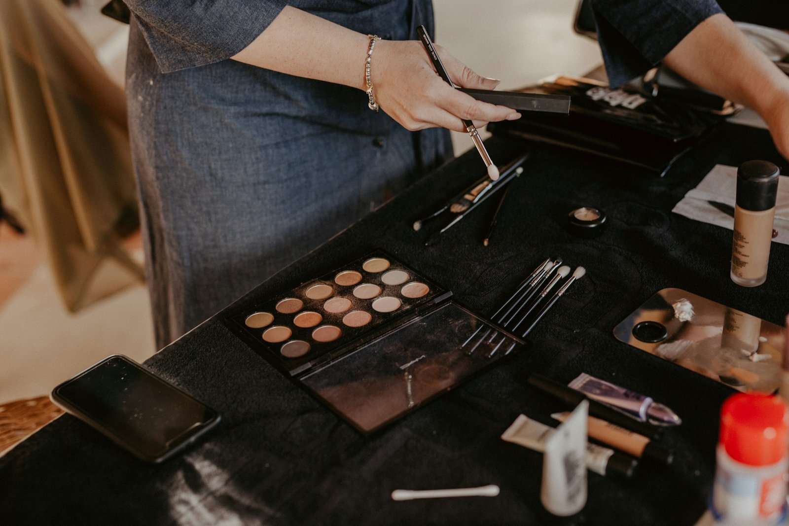 Luxury foundation for mature skin and dry skin: a makeup artist picks a brush beside a foundation bottle and a cream concealer palette