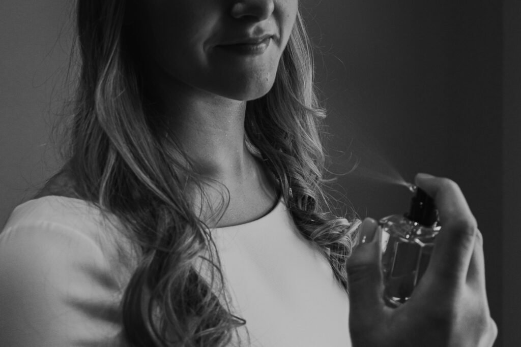 Best luxury hair perfume: a woman with long wavy hair spraying a fragrance mist