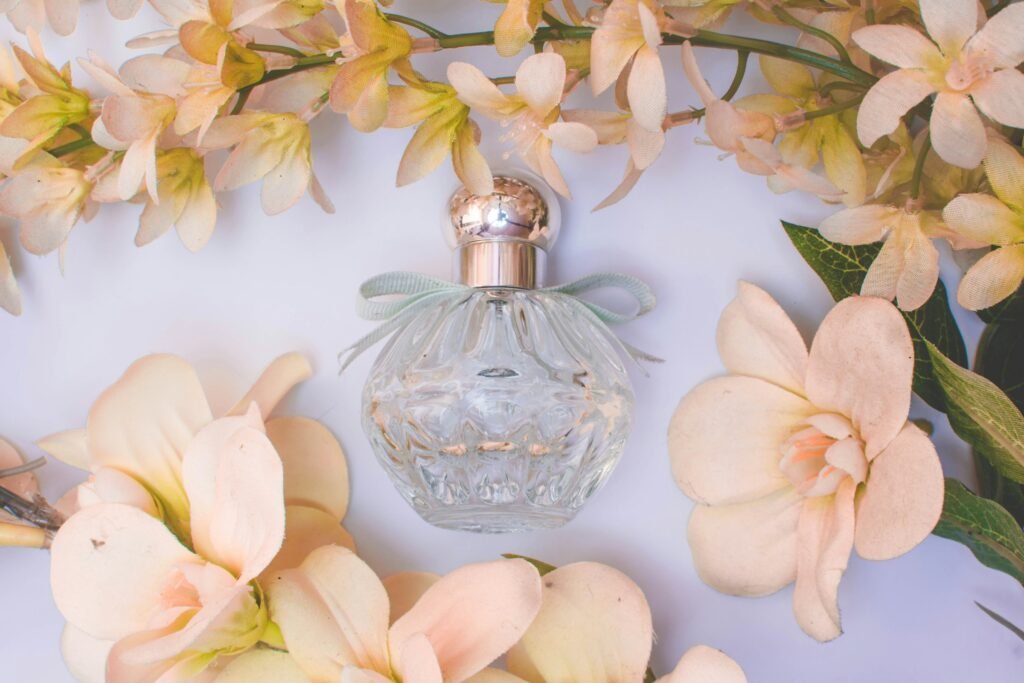 Luxury hair mist alternative: a cut-glass perfume bottle surrounded by soft peach flowers