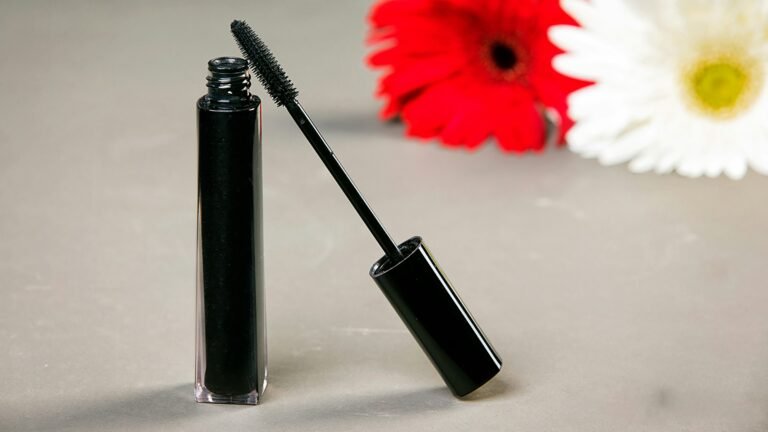 Best luxury mascara: a black mascara tube and wand next to red and white daisies