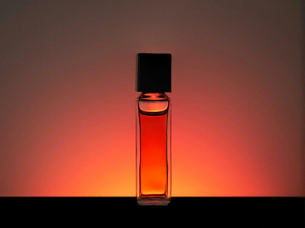 Luxury perfume oil roll on: a slim glass perfume oil bottle glowing amber against a warm backdrop