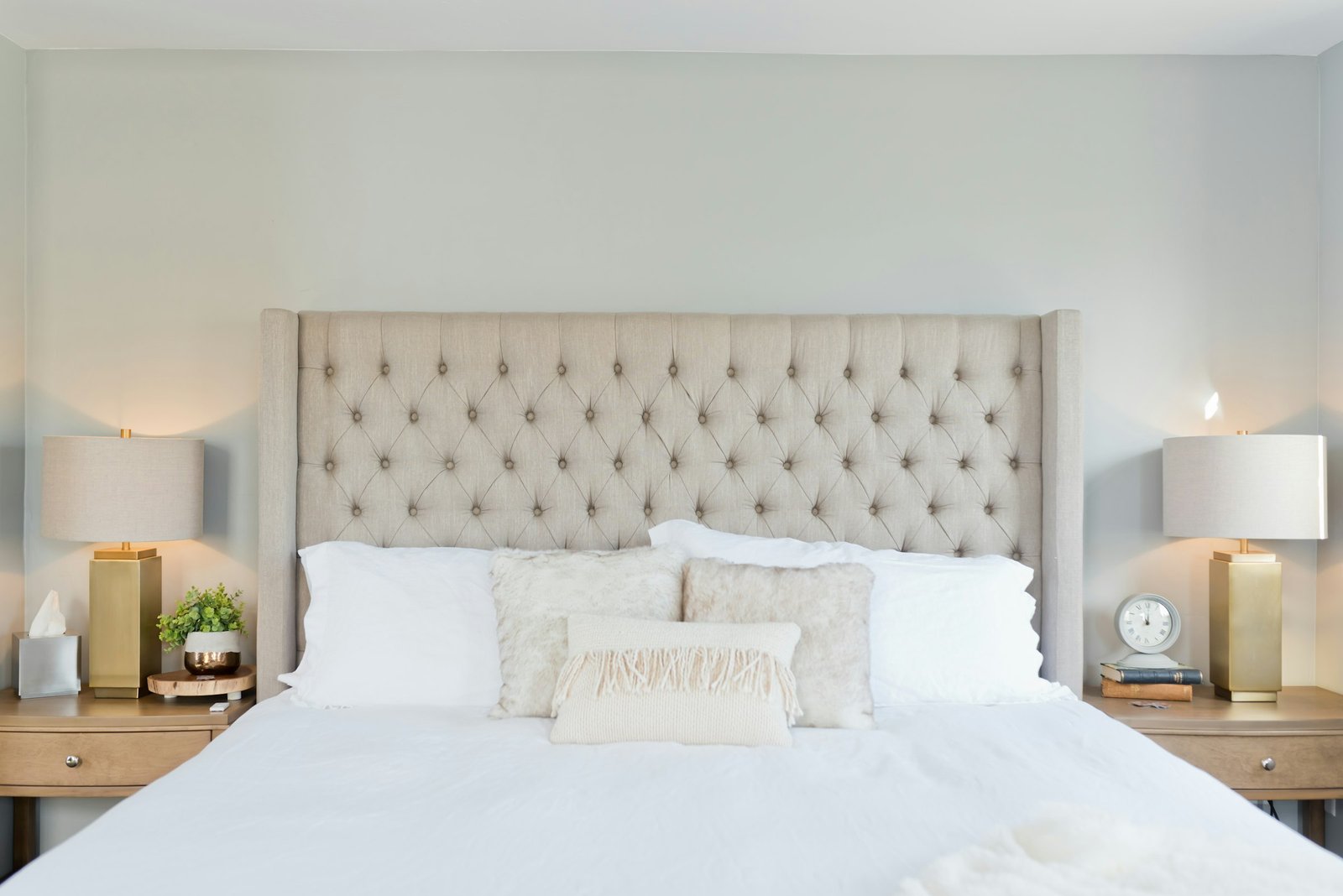 Best mattress protector guide: a neatly made bed with crisp white bedding and a tufted headboard
