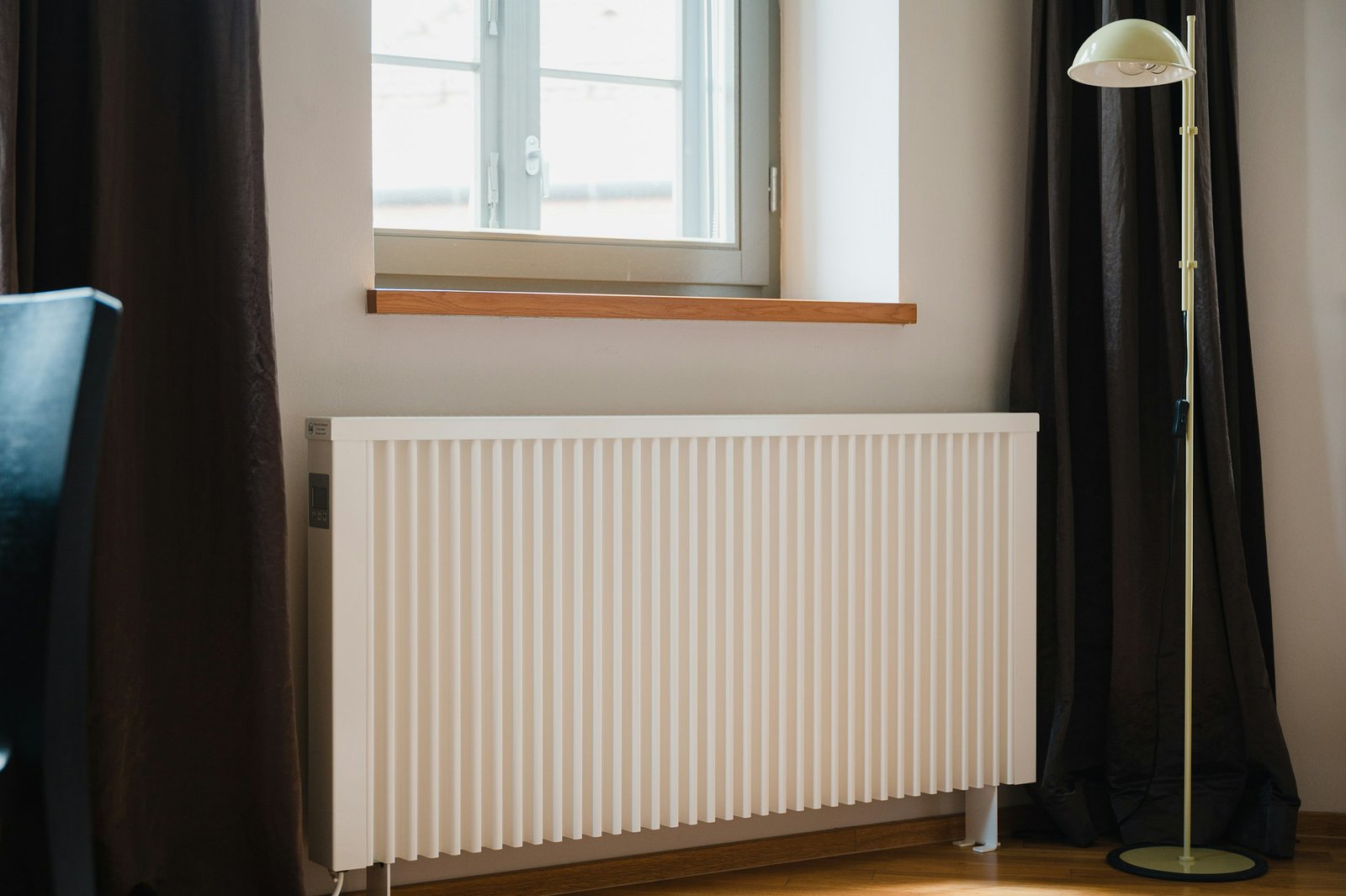 Best oil filled radiator heater style: white fin radiator heater under a bright window in a living room
