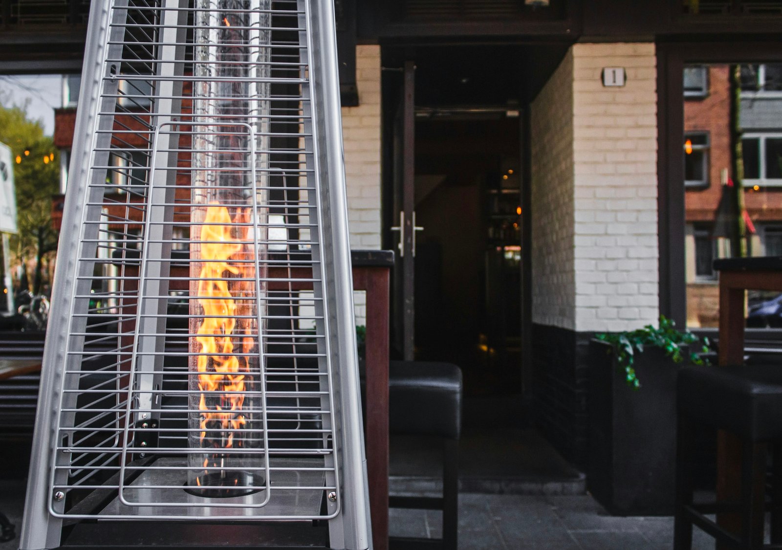 Best patio heater: a pyramid propane patio heater with a glowing glass flame tube outside a restaurant terrace