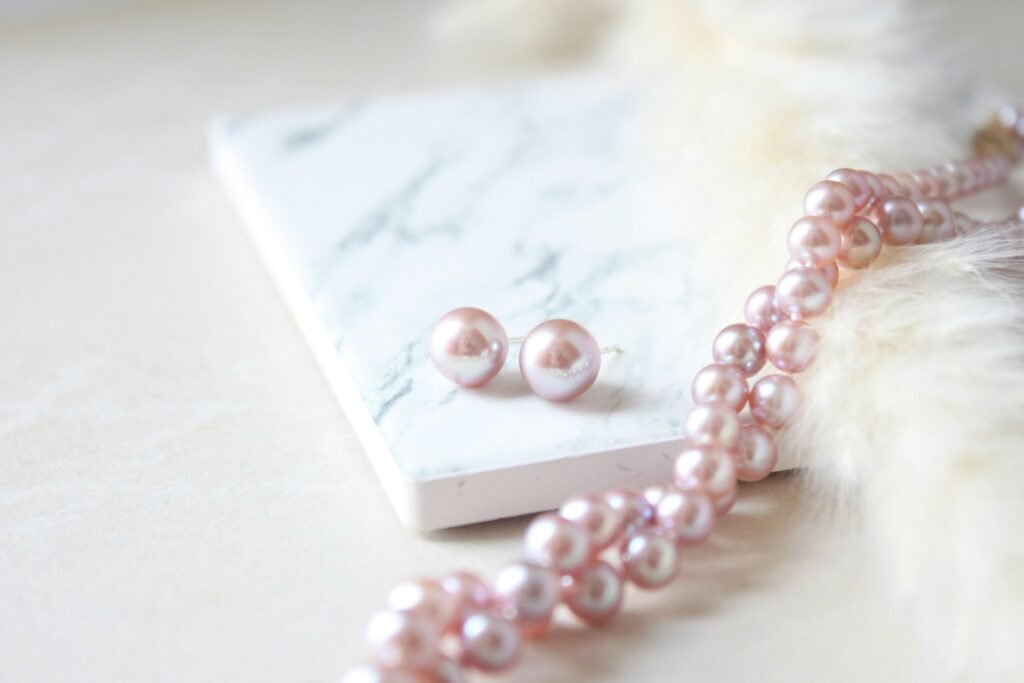 Pink freshwater pearl stud earrings for women on marble with a matching pearl strand