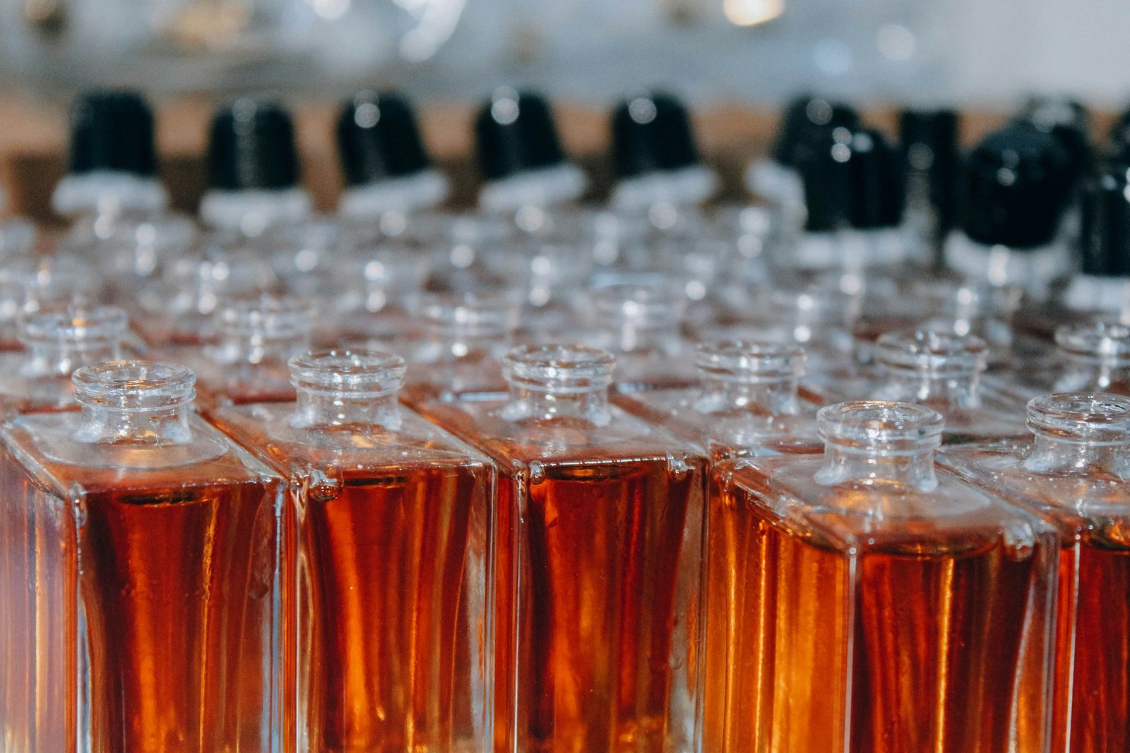 Rows of small glass perfume bottles filled with amber fragrance, like a fragrance discovery set