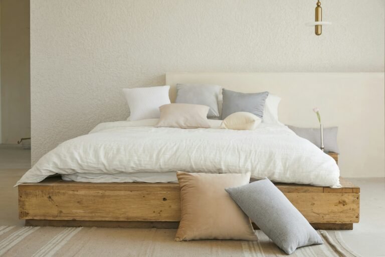 Best platform bed frame: a low solid wood platform bed with white linen bedding and neutral pillows